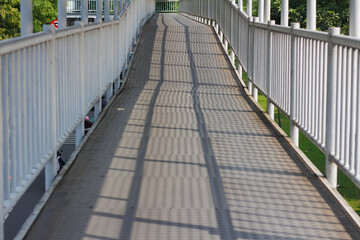 Obraz premium A symmetrical point-of-view shot of a long, narrow covered pedestrian bridge with white railings.