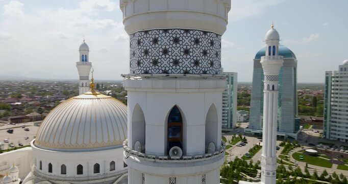 Cinematic aerial orbit shot of the white marble minaret tower detailing geometric patterns at the Pride of Muslims mosque in Shali, Chechnya