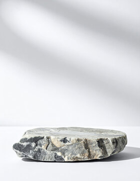 Empty rocky stone podium for product presentation, isolated on white background, minimal composition, centered stone pedestal. Close-up.