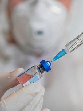 Doctor holding a syringe with a single bottle vial of vaccine and is ready for vaccination. Closeup. Medical concept vaccination hypodermic injection treatment.
