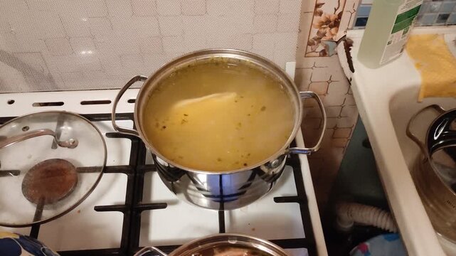 Chicken broth cooking in stainless steel pot on gas stove