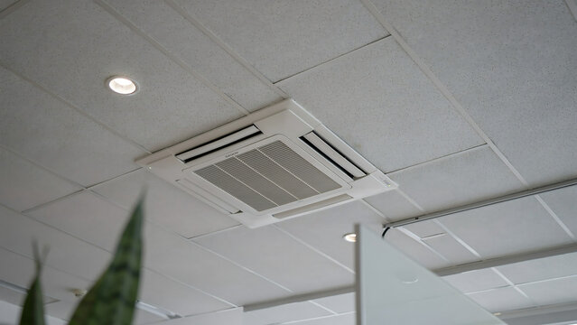 Modern recessed ceiling air conditioner unit in a bright building interior, providing comfortable climate control, efficient cooling and ventilation
