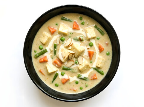 Overhead view of creamy korma curry with tofu vegetables and almonds in a black bowl