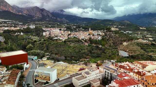 Aerial drone flight over rooftops from La Nucia towards Polop, Spain