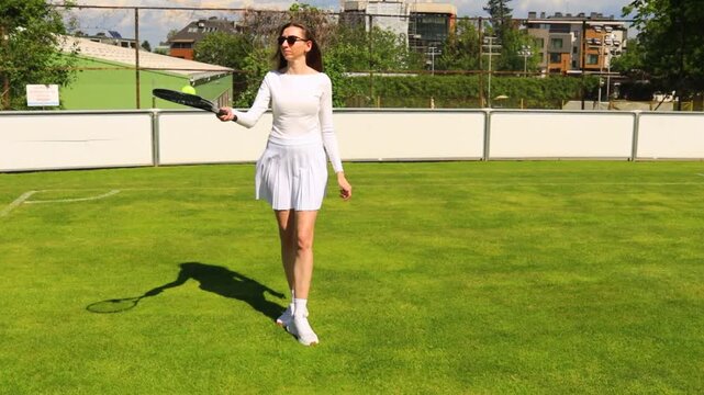Young Woman Practicing Tennis Ball Juggling With Racket on Outdoor Clay Court, Female Athlete in White Sports Outfit Training Coordination and Ball Control During Sunny Day Match Practice, Handheld
