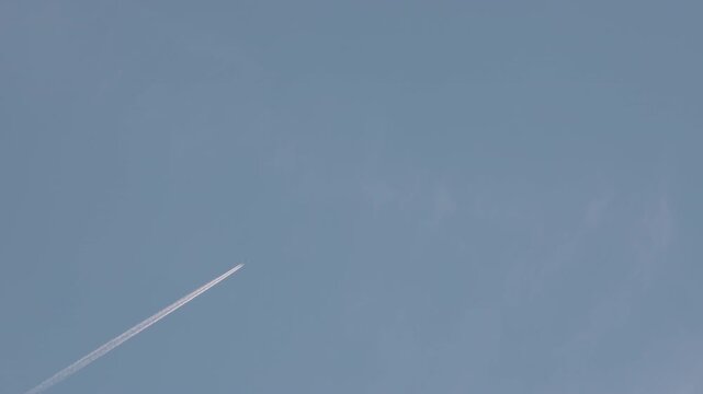 Airplane Flying at High Altitude Leaving Contrail in Blue Sky