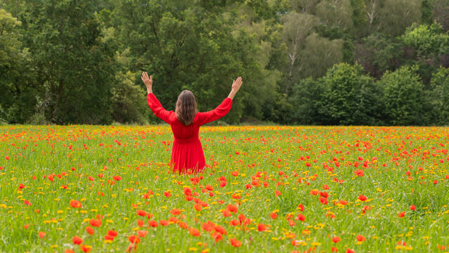happy woman in red dress in wild poppy flower field