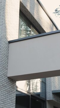 Vertical video. Modern residential building with white brick facade, wood cladding and windows.