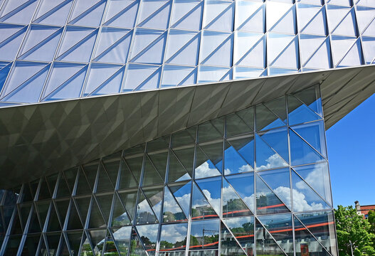 Geneva, Switzerland, Europe :  05.2026 :  Japan International Tobacco (JIT) - headquarters building with self-shading glass facade, trains at Geneva-Secheron train station reflected in glass facade