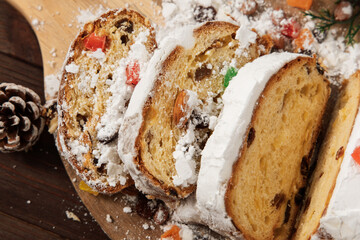 Fototapeta premium Christmas stollen sliced in a kitchen with festive decorations and pinecones on the table