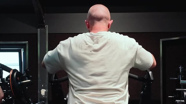 Bodybuilding in the gym - young sporty man performs training for arm