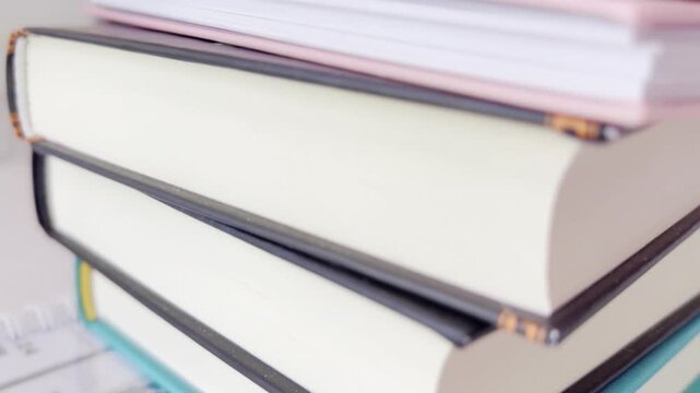 Colorful stack of books, notebooks, and diaries for school and office organization with a shifting focus, showing details of pages, spines, and covers in a close up