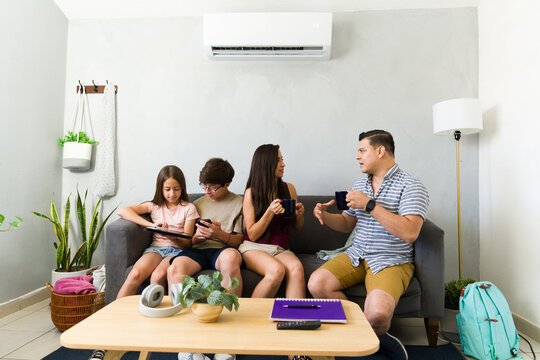 Relaxing family enjoying the cool air from conditioning unit, spending time together in living room during summer heat