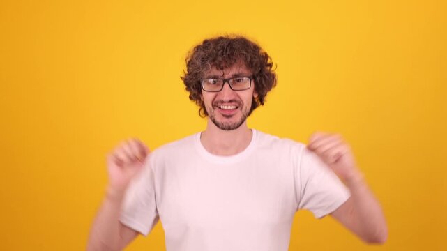 Sincere joyful man raising hands with lively motion and bright yellow backdrop conveying positive emotion, confidence and energetic winner attitude for strong commercial lifestyle themes