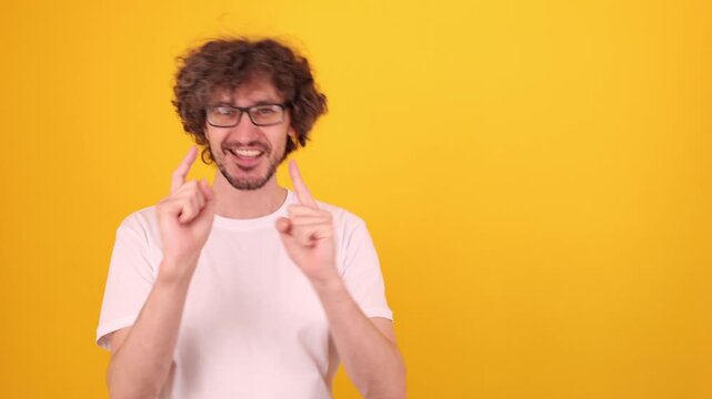   
Person pointing upward with both index fingers in a bright yellow studio portrait, creating an energetic gesture that suggests highlighting space and expressing a positive approving mood.