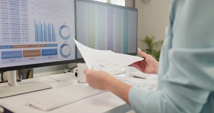 Businesswoman analyst studies finance data reporting dashboard. She compares printed reports with charts on screens, checking budgets and metrics. Clear finance analysis and reporting workflow