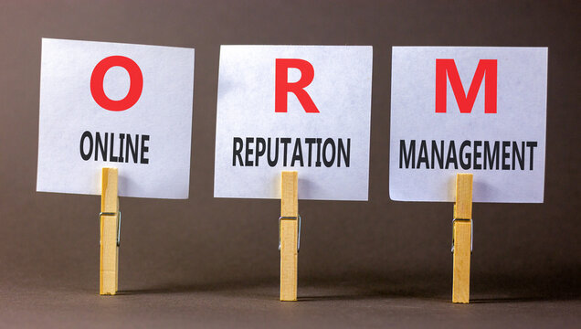 ORM online reputation management symbol. Concept words ORM online reputation management on beautiful white papers on grey clothespins. Beautiful wooden background. Business ORM concept. Copy space.