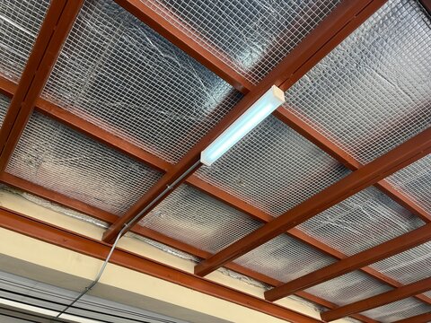 Close-up view of reflective thermal insulation installed beneath a steel roof structure, featuring radiant barrier material and steel support beams. Energy-efficient roofing system designed 