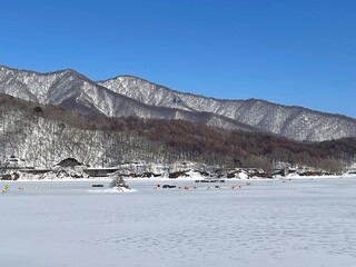 Naklejka premium Stunning winter scenery of frozen Lake Inawashiro under a clear blue sky.