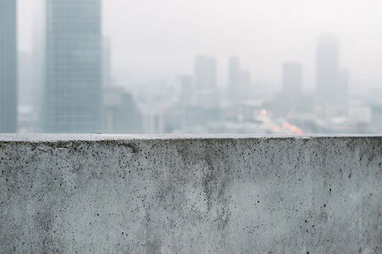 Hazy cityscape view from a concrete rooftop ledge