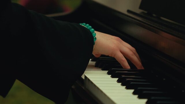 Woman with beaded bracelet playing digital piano close up