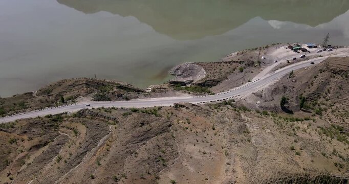 High angle aerial orbit shot of a winding mountain highway serpentine by the Irganai reservoir in Dagestan