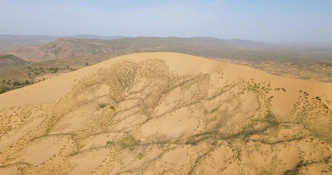 Cinematic aerial fly forward shot approaching the massive sandy slope of Sarykum sand dune in Dagestan