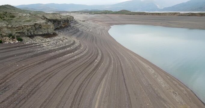 Cinematic wide angle aerial view flying forward over turquoise water of Chirkey reservoir towards layered mountain shores in Dagestan