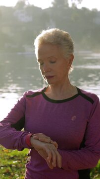 71 year old woman checks her fitness tracker to see how her workout is going. Vertical video.