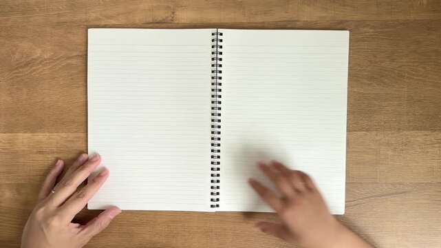 Child Hand Turning One Notebook Page from Right to Left While an Adult Hand Holds the Lower Left Corner, 4K Silent Video