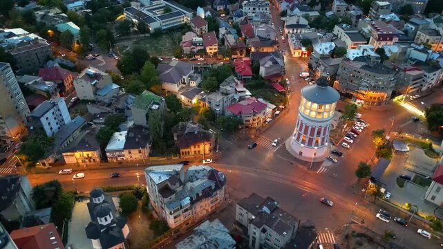Cinematic high angle night view of the illuminated Bucharest fire tower in Romania. Iconic historic brick landmark surrounded by glowing city lights.