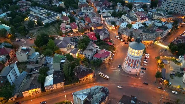 Cinematic high angle night view of the illuminated Bucharest fire tower in Romania. Iconic historic brick landmark surrounded by glowing city lights.