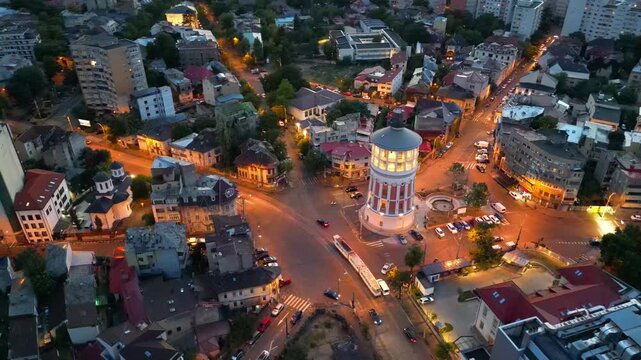 Cinematic high angle night view of the illuminated Bucharest fire tower in Romania. Iconic historic brick landmark surrounded by glowing city lights.