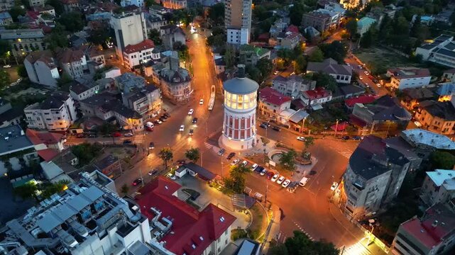 Cinematic high angle night view of the illuminated Bucharest fire tower in Romania. Iconic historic brick landmark surrounded by glowing city lights.
