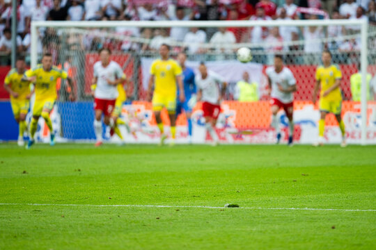 A soccer match scene with players in front of the goal on a stadium with fans.