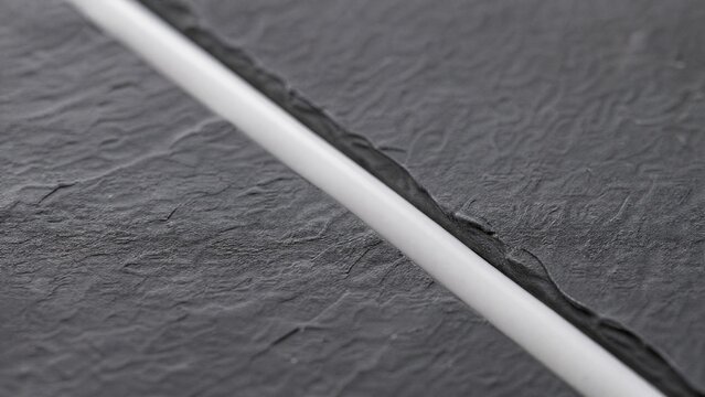 A smooth line of white silicone caulk sealing the seam between two slate tiles.