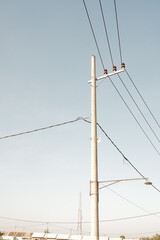 Fototapeta premium Minimalist low angle view of a concrete electric pole with power lines and street light under a clear bright sky background, copy space