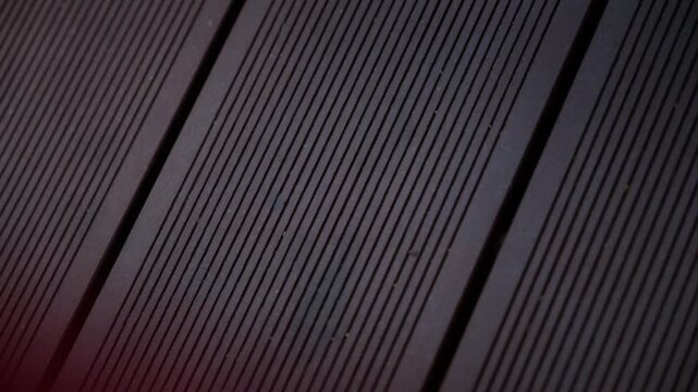 Close up cinematic footage of dark wooden decking boards with linear grooves and geometric patterns