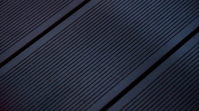Close up cinematic footage of dark wooden decking boards with linear grooves and geometric patterns