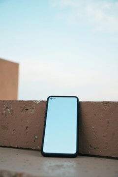 Pantalla en blanco del tel&eacute;fono al aire libre, pared exterior y cielo visibles