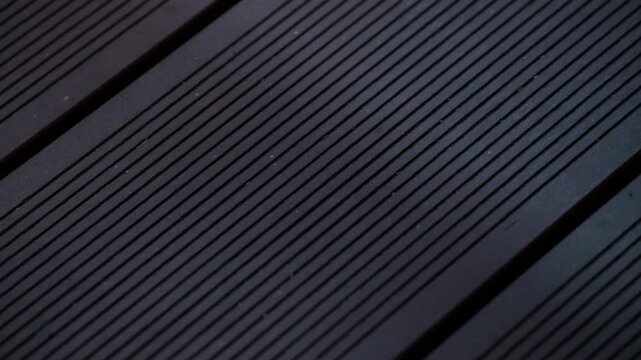 Close up cinematic footage of dark wooden decking boards with linear grooves and geometric patterns