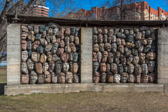 Memorial Wall of Stone Faces Behind Metal Grid Representing Victims of Totalitarian Repression