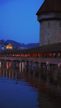Vertical static shot of the historic Chapel Bridge and Reuss river at dusk