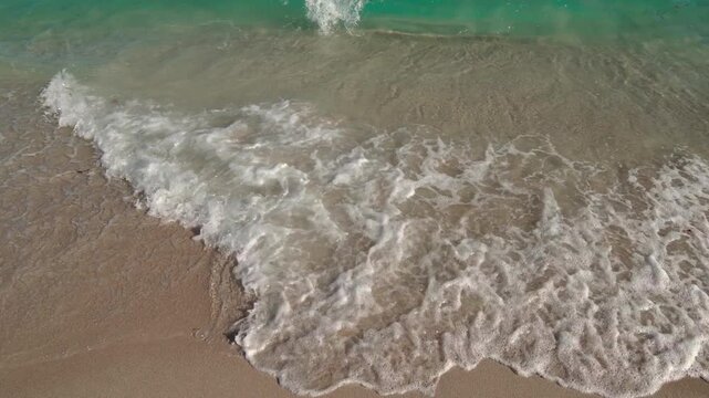 Waves crashing on sandy beach in Miami during sunny daytime hours
