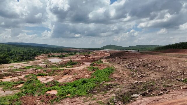 Drone fly forward shot of heavy dump trucks operating on a massive land clearing and construction site.