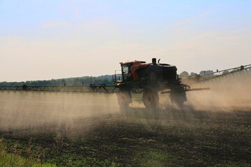 Naklejka premium agricultural machinery fertilizes a farm field with crops