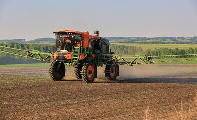 Obraz premium agricultural machinery fertilizes a farm field with crops