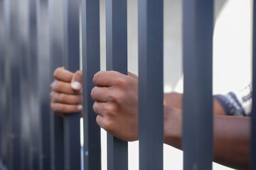 Obraz premium Close-up of hands gripping metal prison bars, symbolizing imprisonment, justice, crime, human rights, freedom restriction, and social issues. Concept of detention, punishment, and captivity.
