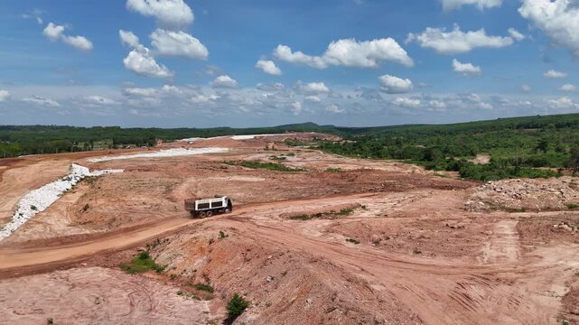 Aerial view of a dump truck operating on a massive mountain reservoir construction site.