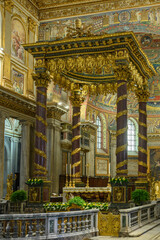 Interior view of the Basilica of Saint Mary Major in Rome, Italy. The magnificent baldacchino altar canopy with porphyry columns, showcasing the medieval golden apse mosaic in the background © Franco Tognarini